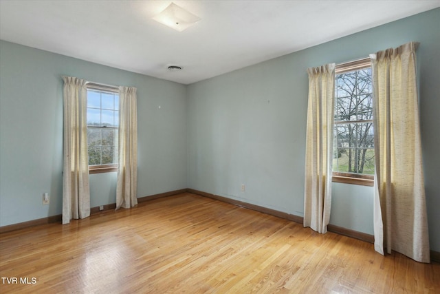 empty room featuring baseboards, a healthy amount of sunlight, and light wood-style floors