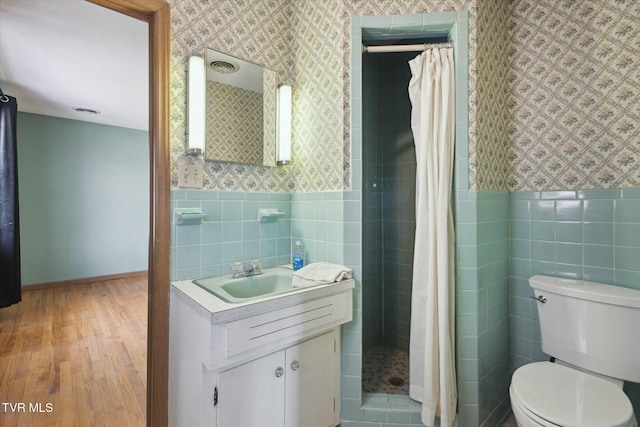 bathroom featuring a shower stall, tile walls, wallpapered walls, and wood finished floors