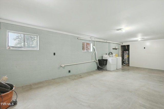 below grade area featuring gas water heater, washing machine and clothes dryer, concrete block wall, and plenty of natural light