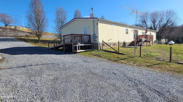 view of property exterior with a deck, a lawn, and gravel driveway