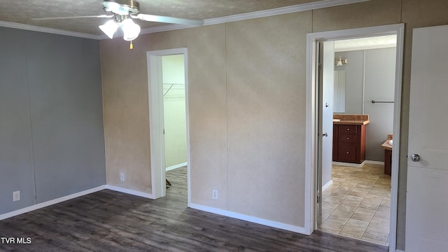 unfurnished bedroom featuring wood finished floors, ornamental molding, a closet, a walk in closet, and ensuite bath