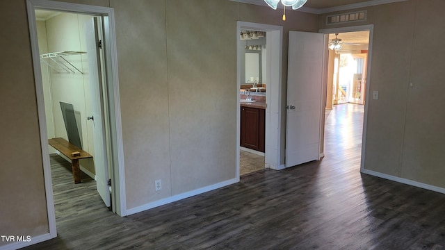 empty room featuring dark wood-type flooring, a sink, visible vents, and baseboards