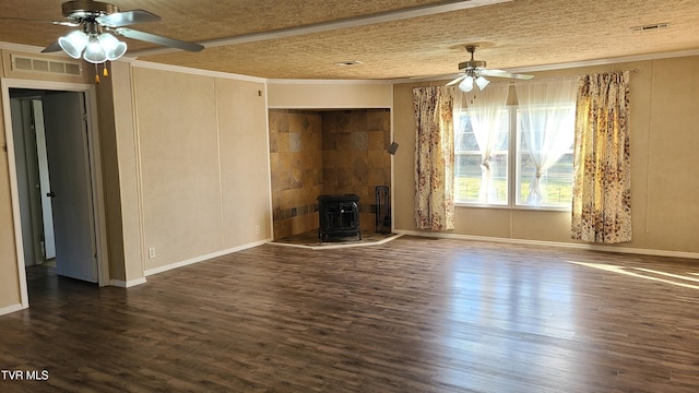 unfurnished living room with ceiling fan, a wood stove, wood finished floors, and visible vents