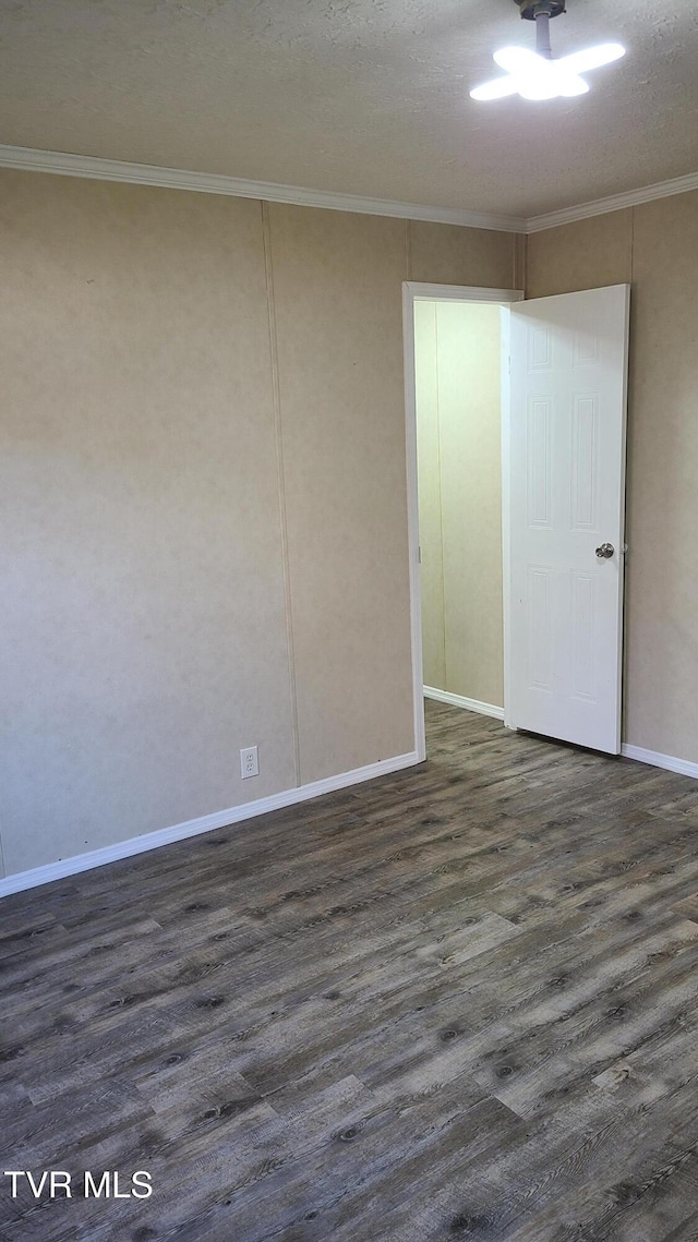 spare room with dark wood-style flooring, crown molding, a textured ceiling, and baseboards