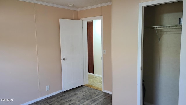 unfurnished bedroom featuring baseboards, a closet, ornamental molding, and wood finished floors