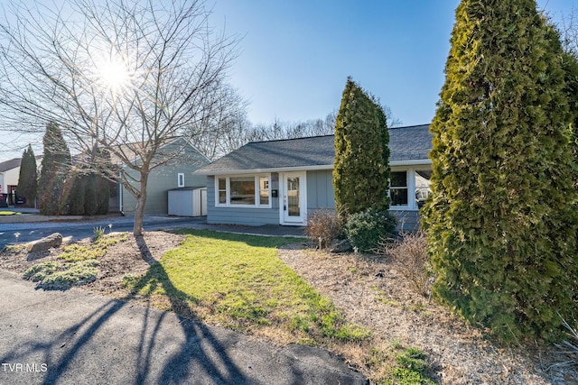 ranch-style home featuring a shingled roof, a front lawn, and board and batten siding