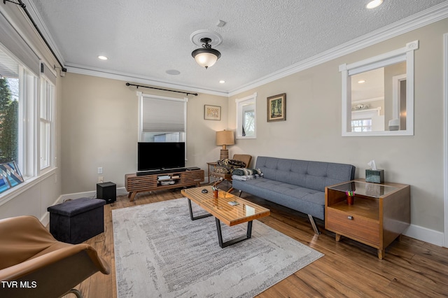 living room with a textured ceiling, baseboards, crown molding, and wood finished floors