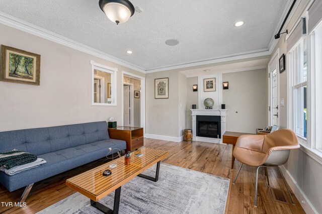 living area with a glass covered fireplace, hardwood / wood-style flooring, and crown molding