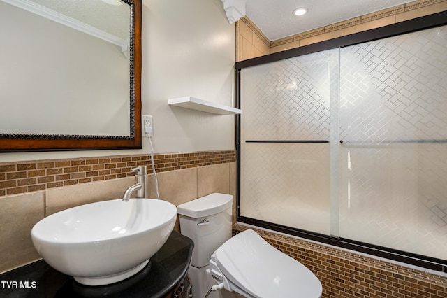 full bathroom featuring tile walls, toilet, a sink, a textured ceiling, and tiled shower