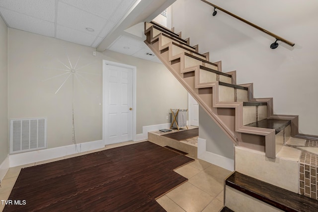 staircase with a drop ceiling, tile patterned flooring, visible vents, and baseboards