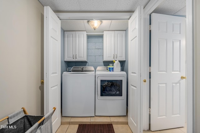 washroom featuring light tile patterned floors, concrete block wall, cabinet space, and separate washer and dryer