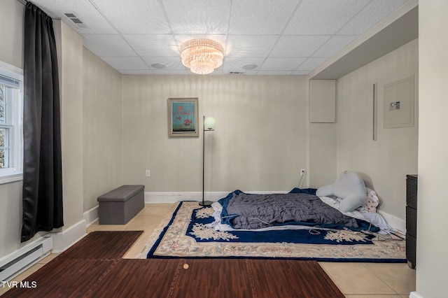 bedroom with tile patterned flooring, a baseboard radiator, visible vents, and a drop ceiling