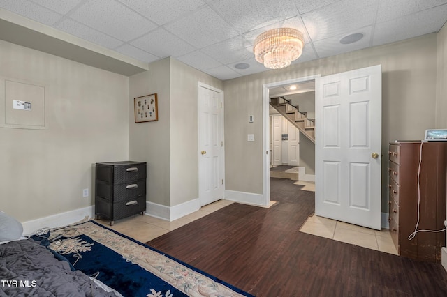 tiled bedroom with an inviting chandelier, baseboards, and a drop ceiling