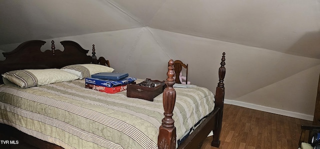 bedroom featuring lofted ceiling, baseboards, and wood finished floors