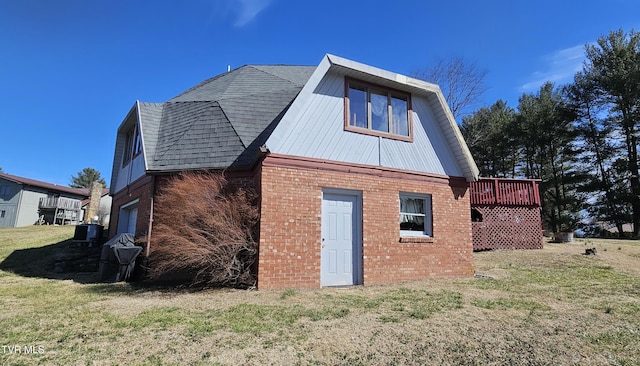 back of house with metal roof, brick siding, roof with shingles, a lawn, and a wooden deck