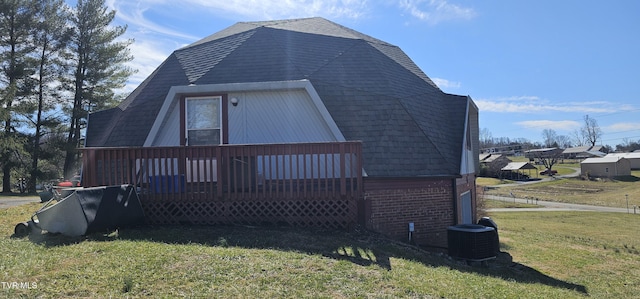 view of home's exterior featuring a yard, brick siding, roof with shingles, and a wooden deck