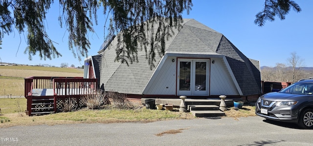 view of front of property featuring a deck and roof with shingles