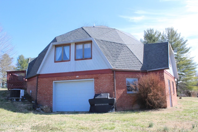 exterior space with brick siding, roof with shingles, a lawn, central AC unit, and driveway