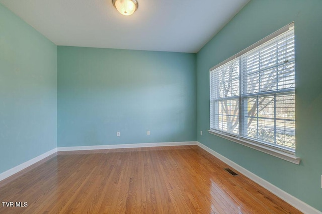 empty room featuring baseboards, visible vents, and wood finished floors