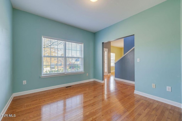 spare room featuring light wood-style flooring, visible vents, and baseboards