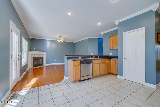 kitchen with light tile patterned floors, dark countertops, open floor plan, stainless steel dishwasher, and a sink