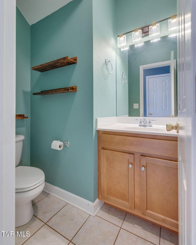 half bath with baseboards, vanity, toilet, and tile patterned floors