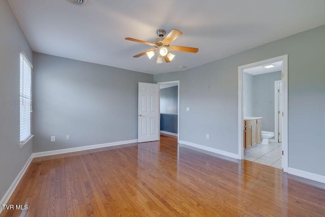 spare room featuring light wood-type flooring, a ceiling fan, and baseboards