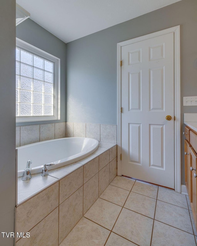 bathroom with a tub to relax in, vanity, and tile patterned floors