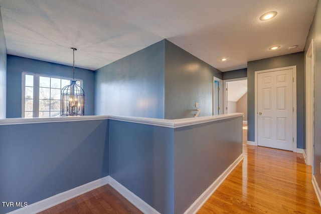 hall featuring recessed lighting, a notable chandelier, an upstairs landing, baseboards, and light wood-style floors