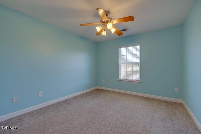 empty room featuring a ceiling fan, light colored carpet, visible vents, and baseboards