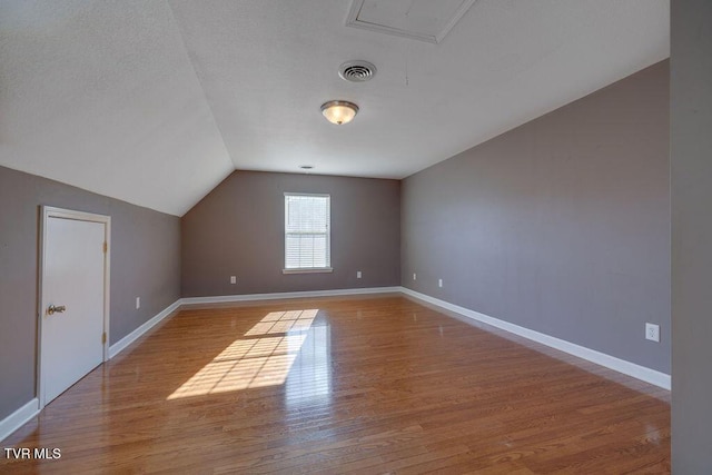 bonus room featuring lofted ceiling, baseboards, visible vents, and wood finished floors