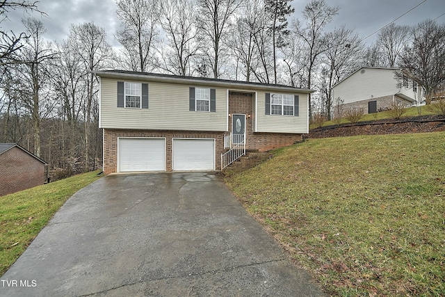 split foyer home with a garage, driveway, a front yard, and brick siding