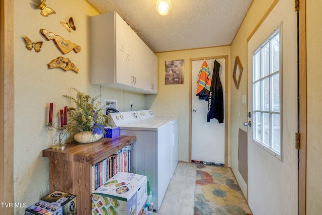 laundry room featuring a textured ceiling, cabinet space, and washer and dryer