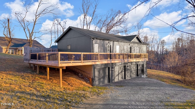 view of side of home with an attached garage, gravel driveway, and a wooden deck