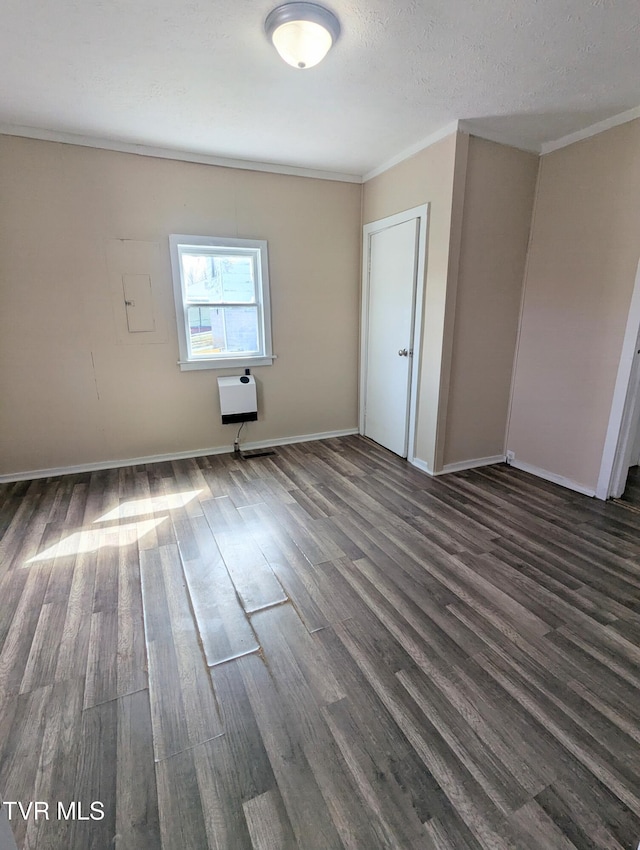 unfurnished room featuring dark wood-type flooring, ornamental molding, a textured ceiling, and baseboards