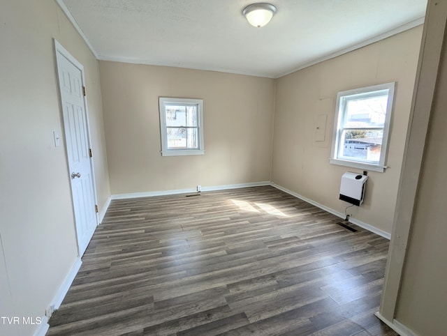 spare room with crown molding, heating unit, dark wood finished floors, and baseboards