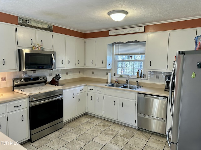 kitchen featuring white cabinets, backsplash, stainless steel appliances, and a sink