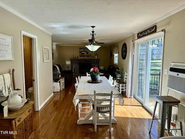 dining room with a brick fireplace, dark wood-style floors, and crown molding