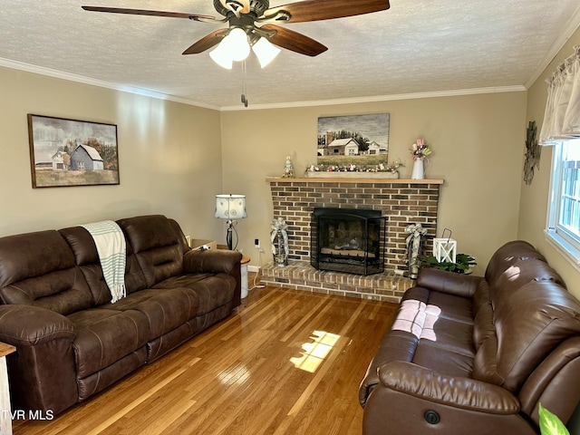 living area with ornamental molding, a fireplace, a textured ceiling, and wood finished floors