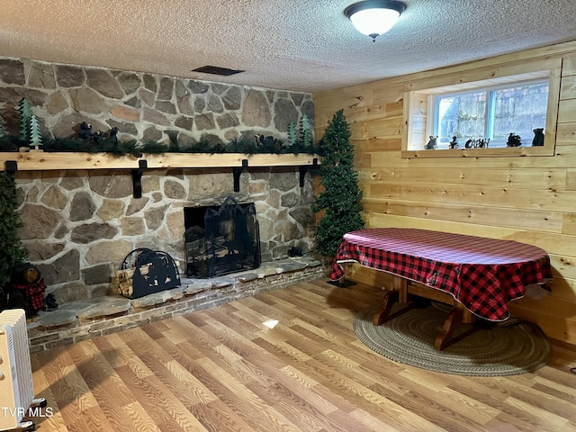 interior space featuring wooden walls, a fireplace, a textured ceiling, and wood finished floors