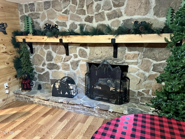 details featuring wooden walls, wood finished floors, and a stone fireplace