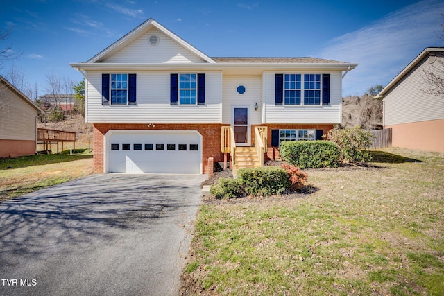 split foyer home featuring driveway, brick siding, a front lawn, and an attached garage