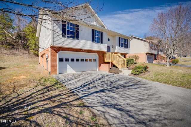 bi-level home with driveway, brick siding, a front lawn, and an attached garage