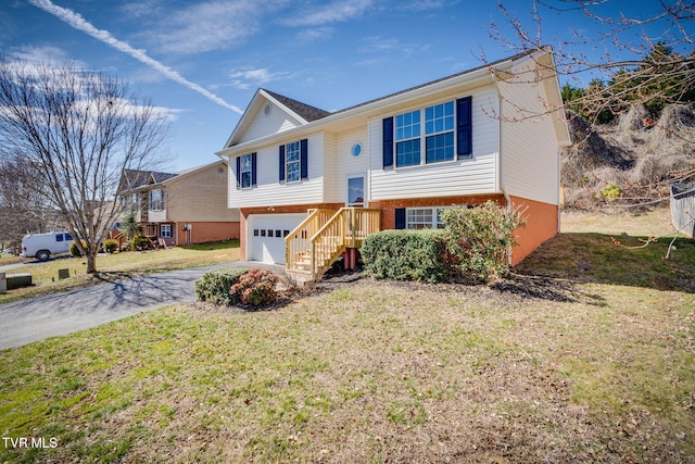 bi-level home featuring a garage, brick siding, driveway, and a front lawn