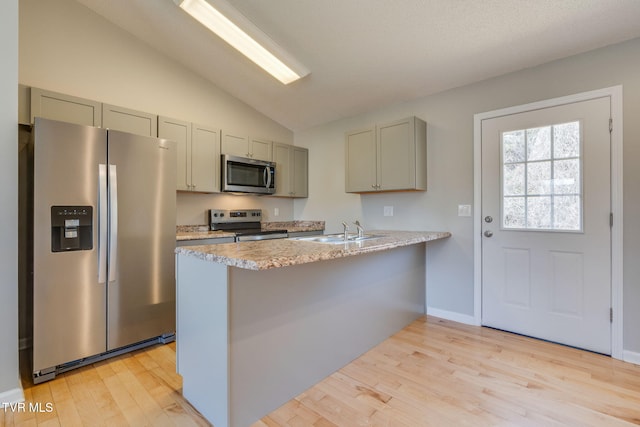 kitchen featuring a peninsula, gray cabinets, stainless steel appliances, light wood-style floors, and a sink