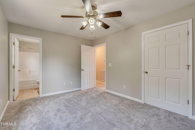 unfurnished bedroom with a textured ceiling, carpet floors, visible vents, baseboards, and ensuite bath