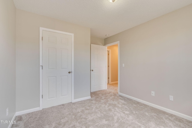 unfurnished bedroom with carpet floors, baseboards, and a textured ceiling