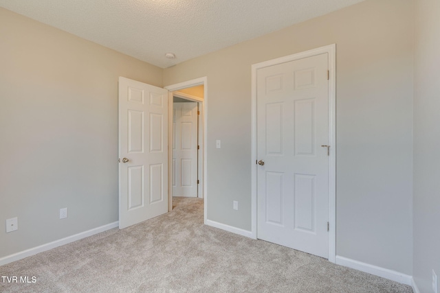 unfurnished bedroom featuring a textured ceiling, carpet floors, and baseboards