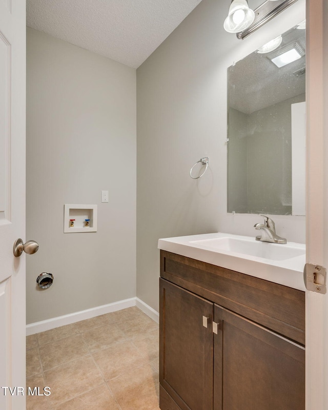 bathroom featuring tile patterned flooring, baseboards, vanity, and a textured ceiling