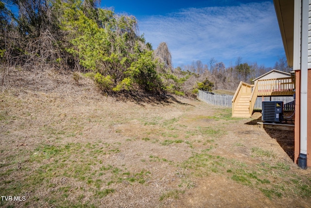 view of yard featuring a deck, central AC unit, stairway, and fence